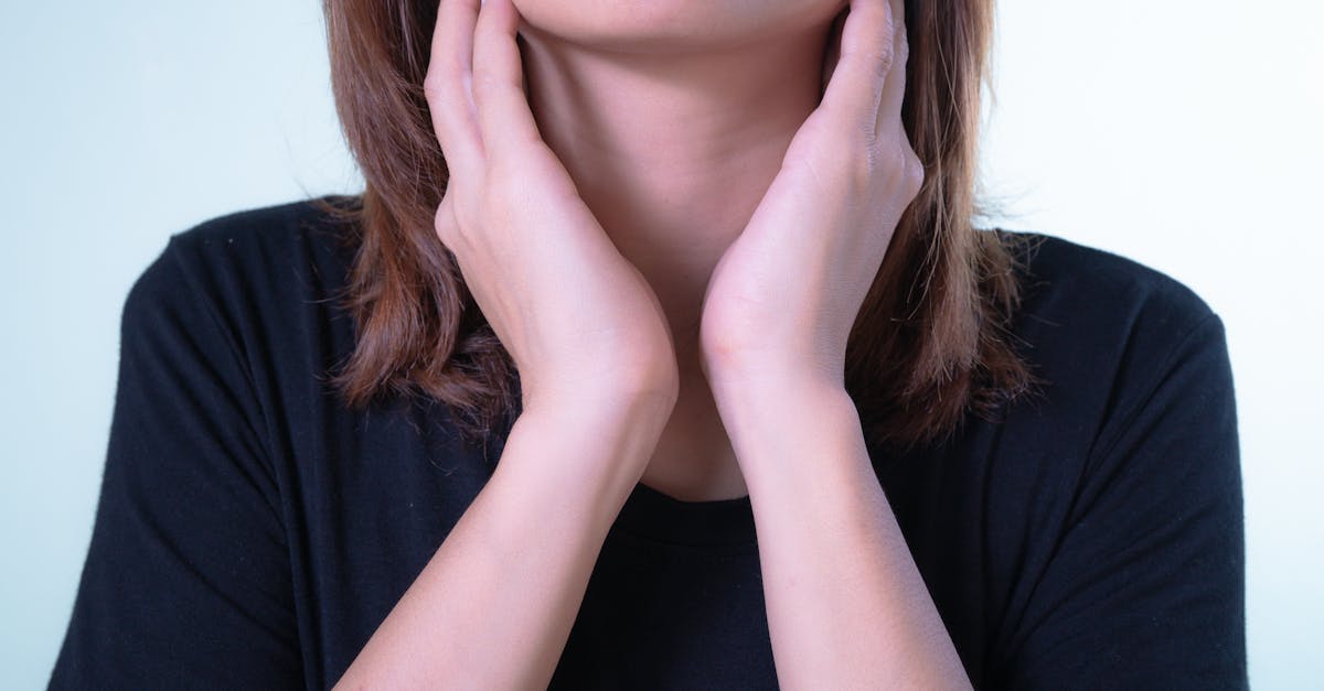 Close-up of a woman touching her neck, possibly indicating discomfort or throat pain.